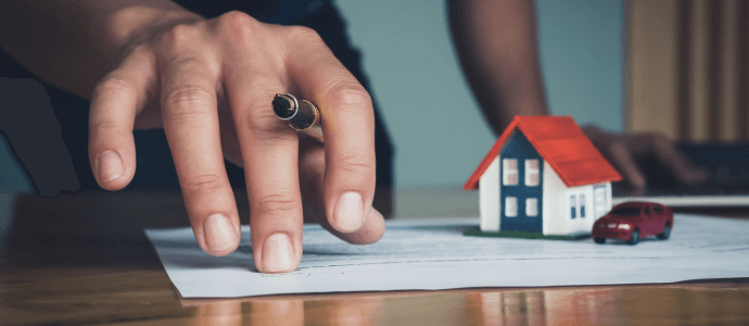 hand with a pen on a contract with a house