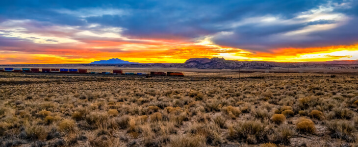 A train moving through the desert at sunset.