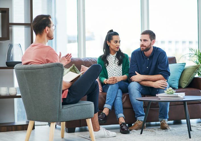 Shot of two young men and a woman having a discussion in a modern office, discussing divorce mediation
