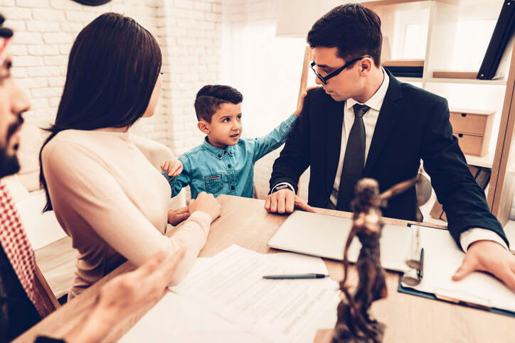 Family in Lawyer Office. Couple is Arab Husband, Wife and Son. Lawyer is Caucasian Man in Suit. Man is Wearing Traditional Arab Clothes. Son is Showing Lawyer that Choosing Mother.