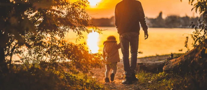 dad holding little girls hand during a sunset