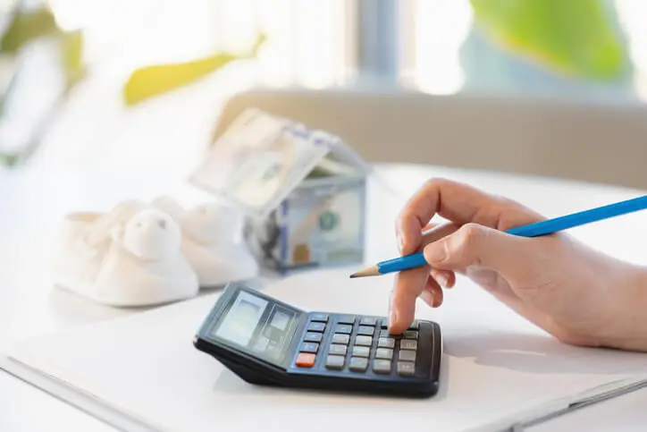 A woman preparing to give birth is tapping a calculator while considering buying a home