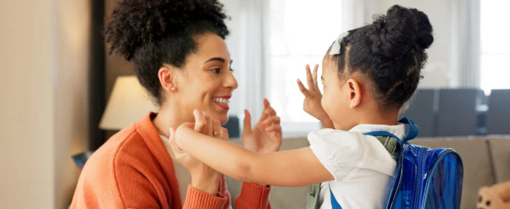 Little girl kissing her mother. Young mother hugging her daughter. Loving mother hugging daughter before school outside. Little girl going to school. Happy woman embracing daughter