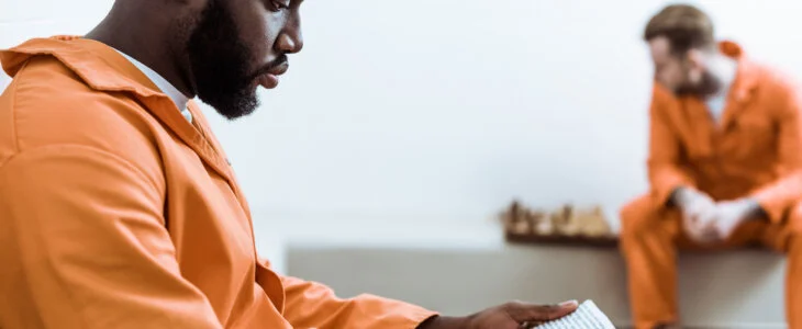 side view of african american prisoner reading book